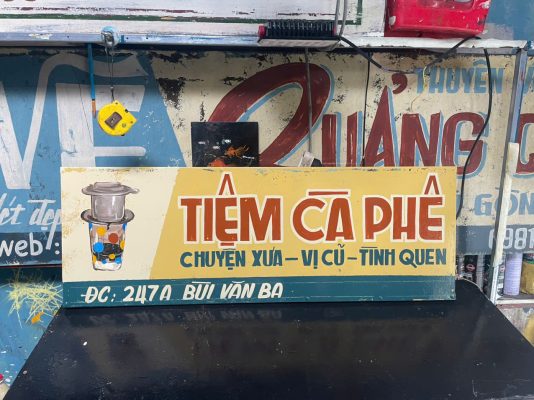 Vẽ bảng hiệu tiệm cà phê xưa phong cách Sài Gòn bên Vespa cổ Bảng hiệu vẽ tay vintage nền vàng chữ đỏ hoài niệm Thiết kế bảng hiệu cà phê retro với minh họa phin truyền thống Bảng hiệu phong cách bao cấp vẽ sơn dầu thủ công